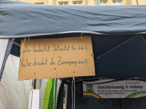 Am Stand hängt ein Pappschild. Darauf steht: "Was bedeutet Intimität für dich? Wie drückst du Zuneigung aus?"